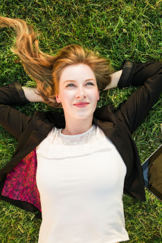 Young,Independent,Woman,Relaxing,On,Grass,In,Park